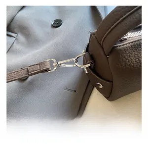 Detail of dark brown leather bag showing silver swivel hook and precision stitching