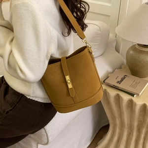 Chic mustard yellow matte bucket bag with gold twist lock shown on a model's shoulder