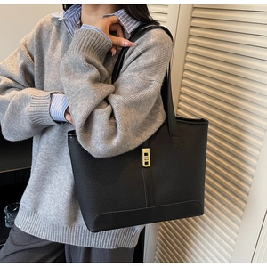 Detail of black pebbled leather tote bag with gold twist lock and vertical stripe