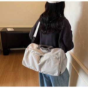 Action shot of beige fitness travel bag with shoulder strap and checkered front pocket