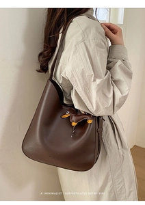 Detail of vintage brown leather bucket bag featuring a dachshund charm and embossed logo