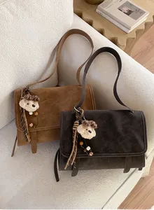 Detail of vintage suede shoulder bags in brown and dark grey with plush bear charms