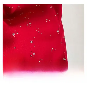 Macro detail of red knit tote bag featuring silver star patterns and a lace brand label