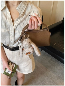 Close-up of brown litchi pattern Boston bag with cute plush rabbit charm accessory