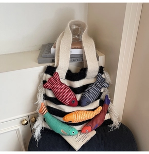 Detail of knitted tote bag with colorful 3D fish ornaments and white feather fringe