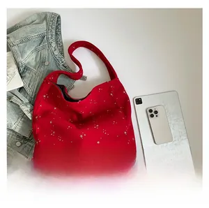 Detail view of red tote bag with silver star patterns laid flat with iPad for scale