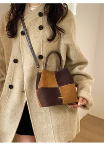 Detail of color-block bucket bag with gold metal logo on elegant beige coat