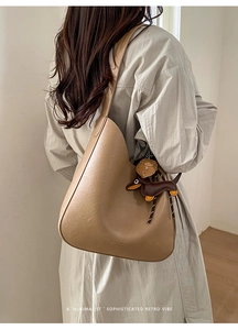 Detailed view of retro brown leather crescent bag with cute dachshund charm on model