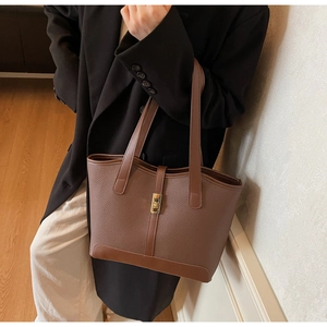 Detail of dark brown lychee leather tote bag with elegant metal twist lock closure
