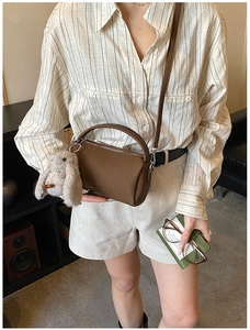 Close-up of brown pebbled leather Boston bag with metal zipper and plush rabbit charm