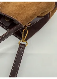 Detailed close-up of golden metal lobster clasp and contrast stitching on vintage bag
