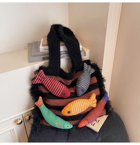 Detail of knitted tote bag featuring striped pattern and colorful plush fish ornaments