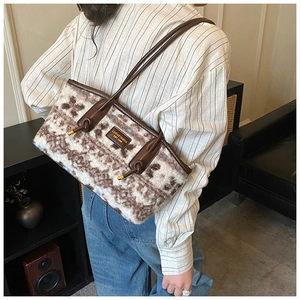 Detail of wool tote bag with brown leather handles and brand patch shown on model