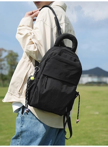 Détail du sac à dos en nylon noir avec poignée renforcée et pendentif de balle de tennis
