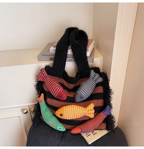 Detail of striped knitted tote bag with black fringe and colorful 3D stuffed fish dolls