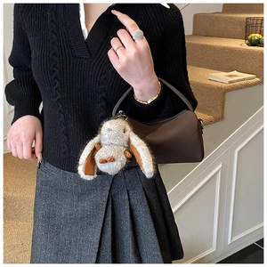 Litchi pattern leather handbag with a plush rabbit charm shown with model outfit
