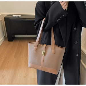 Close-up of brown litchi pattern leather tote bag with elegant gold metal buckle