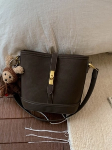 Vintage matte brown leather bucket bag with gold hardware lock and monkey charm detail