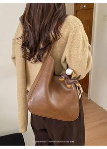 Detailed shot of brown wax leather shoulder bag with cute dachshund bag charm