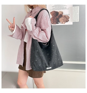 Detail of dark grey tote bag with white star pattern and cloth label on inner edge