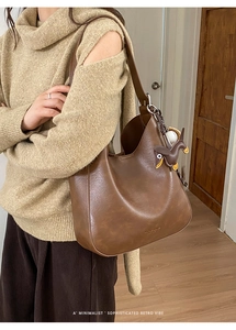 Detail of brown vintage leather bucket bag with cute puppy and baseball charms