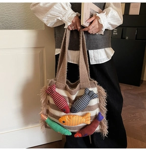Close-up of knit tote bag with colorful fish patches and fringe texture details