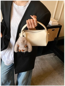 Detail of off-white lychee leather Boston bag with cute grey plush rabbit charm
