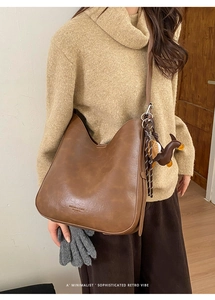 Brown vintage leather tote bag with long strap and horse charm detail on model