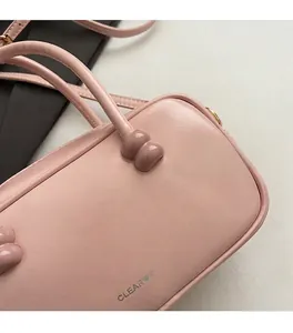 Detail of pink Boston bag with silver logo, smooth leather texture and refined handles
