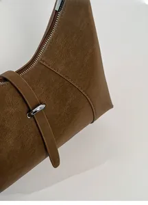 Detailed close-up of brown pebbled leather texture and silver zipper on the tote bag