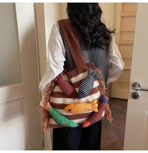 Detail of striped knit tote bag featuring 3D fish accents and long side tassels