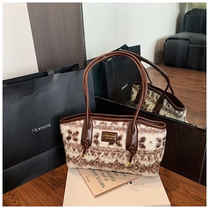 Detailed view of plush tote bag with floral pattern and leather strap on a box