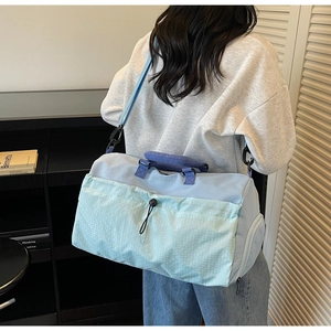 Rear view of model wearing a light blue fitness travel bag with mint green plaid pocket