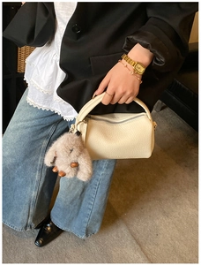 Detail of beige lychee textured mini bag with cute grey plush bunny charm