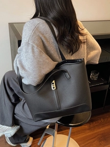 Minimalist black pebbled leather tote bag with gold lock and spacious interior