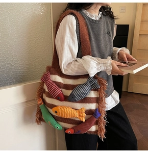 Close-up of knit tote bag featuring 3D colorful fish motifs and side tassel details