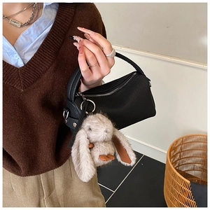 Detail of black pebbled leather mini crossbody bag with cute plush rabbit charm