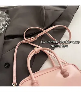 Close-up of pink Boston bag showing top handles with spherical bead charms and strap