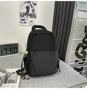 Détail du sac à dos noir avec tissu à carreaux et accessoire de charme raquette de tennis
