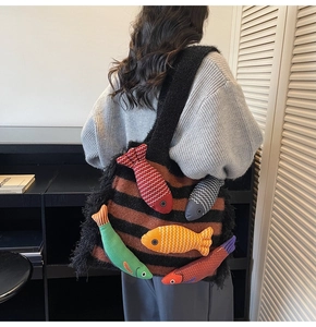 Detailed view of woven tote bag featuring colorful 3D fish charms and side tassels