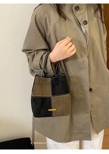 Detail of retro color-block bucket bag with contrast stitching and golden hardware