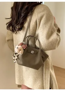 Detailed view of dark brown litchi pattern leather bag with silver buckle and plush bear charm