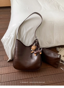 Detail view of a vintage dark brown shoulder bag set with a cute dog leather pendant