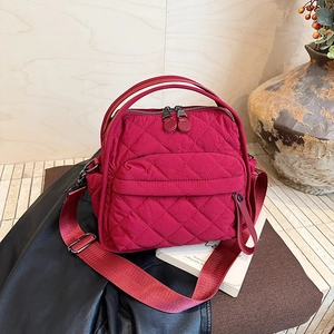Detail of fuchsia quilted nylon bag with dual zippers and adjustable wide strap