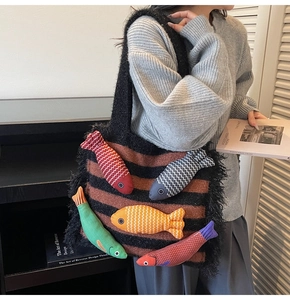 Artistic striped knitted tote bag featuring colorful 3D fish appliqués and fringe details
