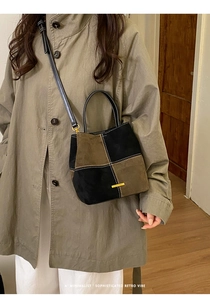Detail of color-block bucket bag with matte suede texture and elegant gold hardware