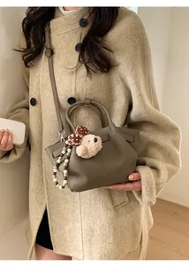 Detail of dark taupe lychee texture bag with plush bear charm and beaded chain accessory