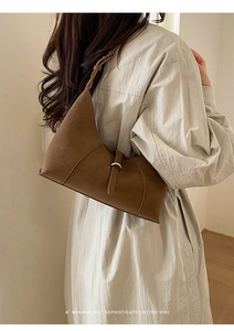 Close-up of a dark brown matte leather half-moon shoulder bag with metal buckle
