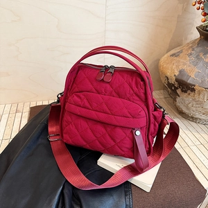 Macro shot of red quilted nylon handbag featuring diamond stitching and comfort strap