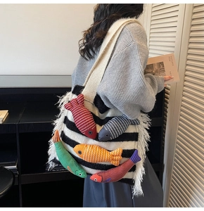 Detail of plush black and white striped tote bag with colorful 3D fish and white tassels
